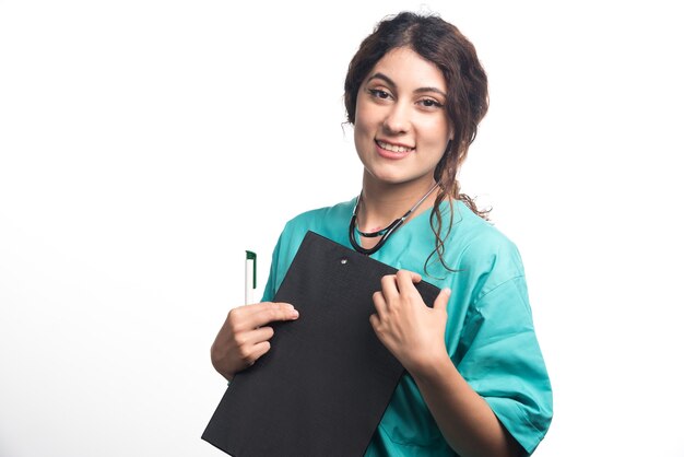 Jeune femme médecin avec presse-papiers tenant un stylo dans sa main sur fond blanc. Photo de haute qualité