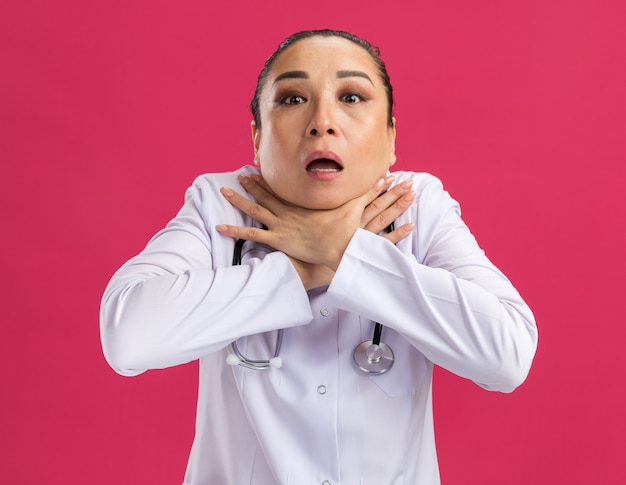Jeune femme médecin s'étouffant tenant la main sur le cou en panique