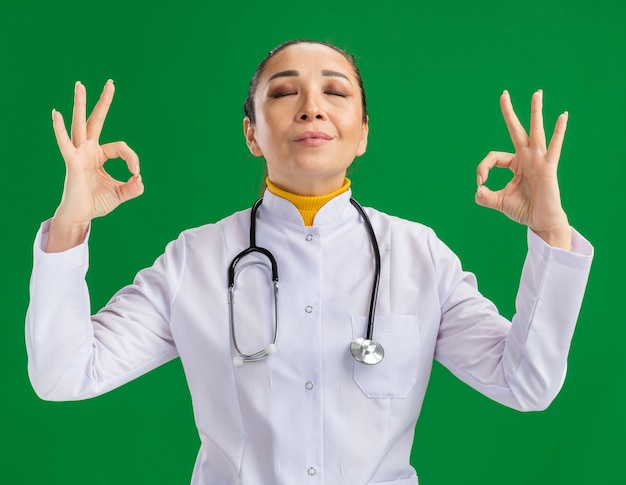 Jeune femme médecin se relaxant les yeux fermés faisant un geste de méditation avec les doigts