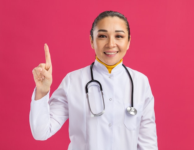 Jeune femme médecin souriant joyeusement montrant l'index