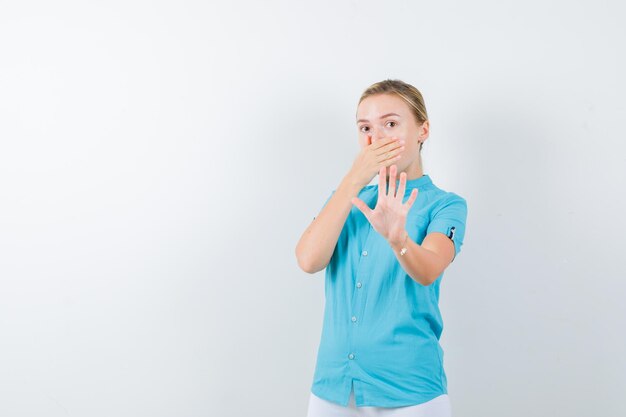 Jeune femme médecin tenant la main sur la bouche tout en montrant le geste d'arrêt