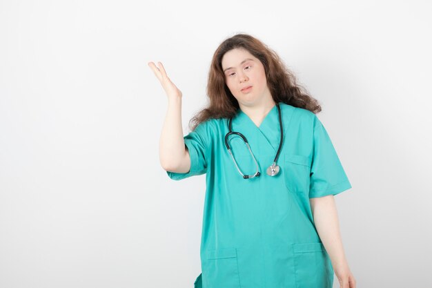 Jeune femme médecin trisomique debout sur blanc.