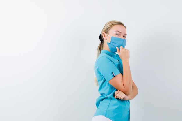 Jeune femme médecin en uniforme debout dans une pose de réflexion et à l'air confiant