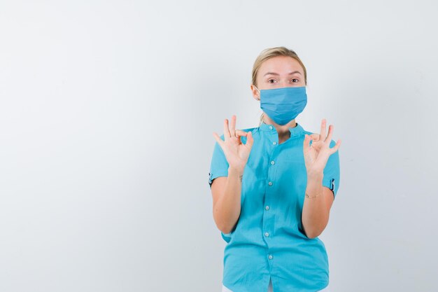 Jeune femme médecin en uniforme montrant un geste ok et ayant l'air confiant isolé