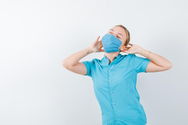 Jeune femme médecin en uniforme tenant les mains derrière la tête et à la recherche de sommeil isolé