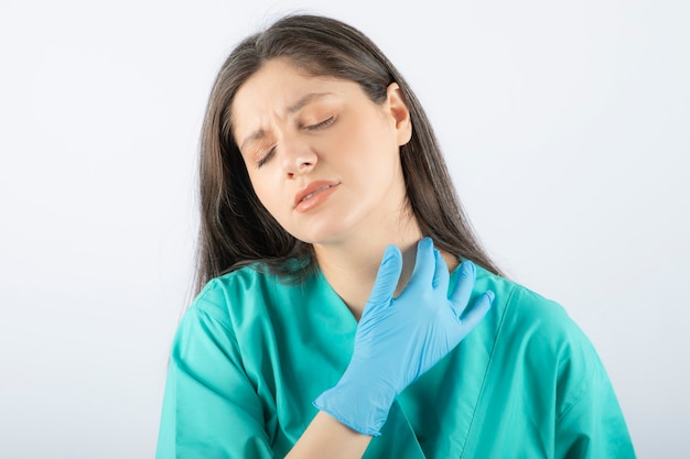 jeune femme médecin en uniforme vert touchant son cou.