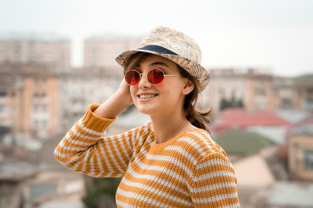 Une jeune femme mignonne dans une casquette et des lunettes posant à l'extérieur. photo de haute qualité