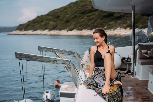 Jeune femme mince assise en bikini maillot de bain sur un yacht et se prélassant au soleil