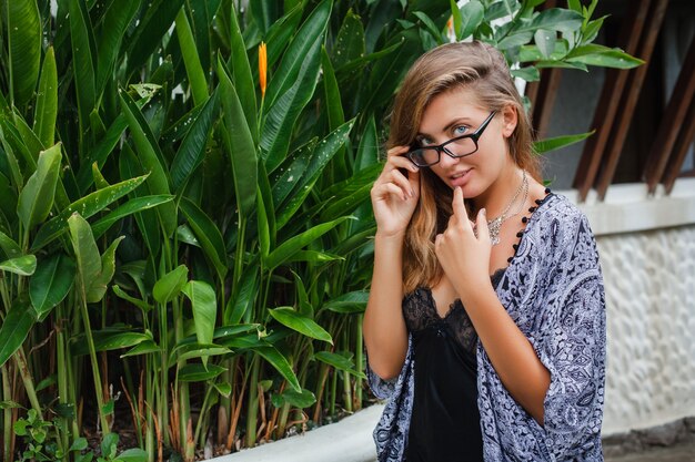 Jeune femme mince dans une villa tropicale de Bali, portant des lunettes et de la lingerie