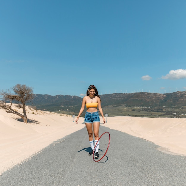 Jeune femme mince roulant hula hoop sur route