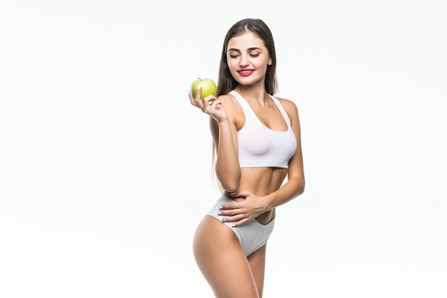 Jeune femme mince tenant une pomme verte. Isolé sur un mur blanc. Concept d'alimentation saine et contrôle de l'excès de poids.