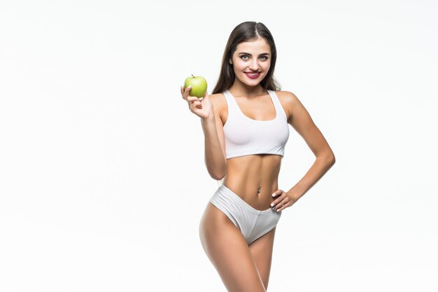 Jeune femme mince tenant une pomme verte. Isolé sur un mur blanc. Concept d'alimentation saine et contrôle de l'excès de poids.