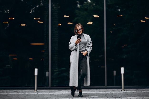 Jeune femme à la mode en manteau gris, parler au téléphone