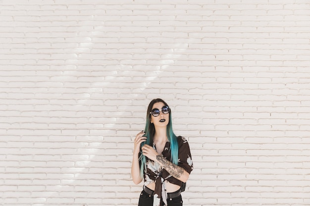 Photo gratuite jeune femme moderne avec tatouage sur la main, posant devant le mur