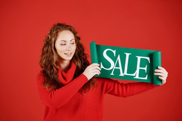 Photo gratuite jeune femme montrant une bannière de vente au studio shot