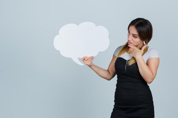 Jeune femme montrant la bulle de dialogue tout en maintenant le doigt sur le menton