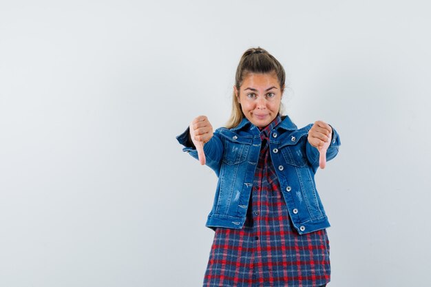 Photo gratuite jeune femme montrant deux pouces vers le bas en chemise, veste et à la vue confiante, de face.