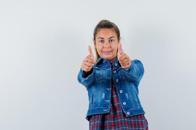 Jeune femme montrant deux pouces vers le haut en chemise, veste et à la vue de face, confiant.