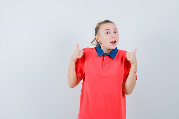 Jeune femme montrant deux pouces vers le haut en t-shirt et à la joyeuse