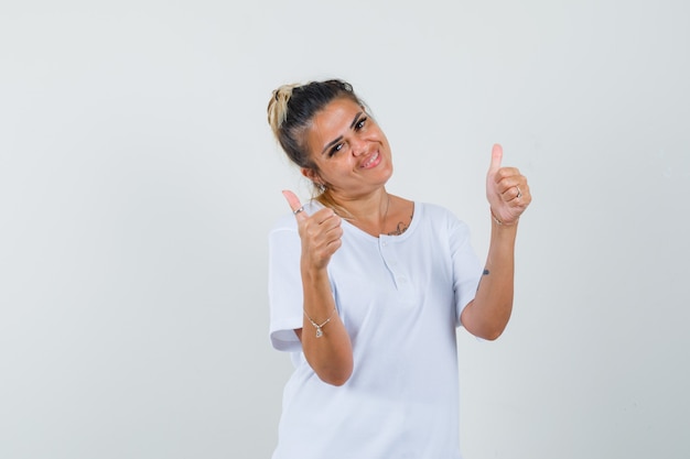 Jeune femme montrant deux pouces vers le haut en t-shirt et à la recherche de plaisir