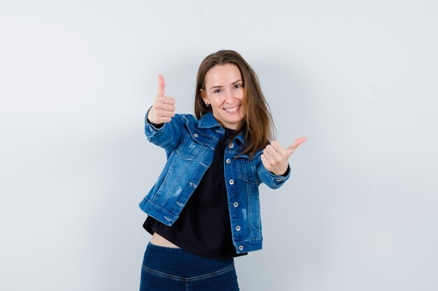 Jeune femme montrant un double coup de pouce en blouse et l'air confiant. vue de face.