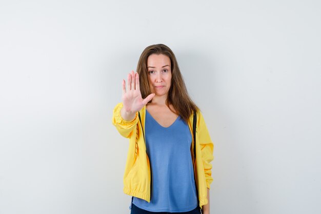 Jeune femme montrant un geste d'arrêt et ayant l'air confiant. vue de face.