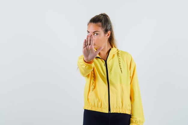 Photo gratuite jeune femme montrant le geste d'arrêt en imperméable jaune et à la grave