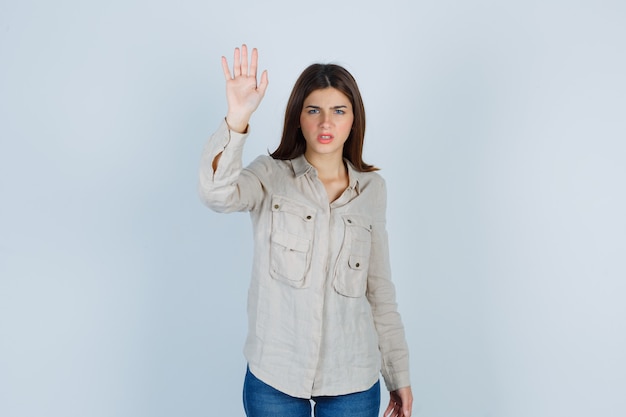 Jeune femme montrant un geste d'arrêt en jeans décontractés et semblant sérieuse. vue de face.