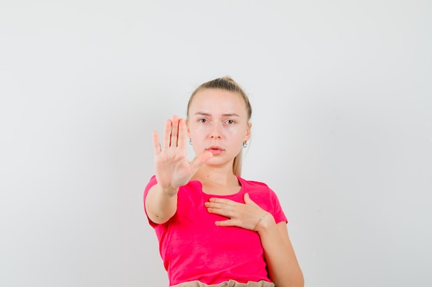 Photo gratuite jeune femme montrant le geste d'arrêt en t-shirt et à l'ennui