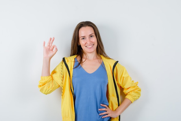 Jeune Femme Montrant Un Geste Correct En T-shirt, Veste Et L'air Confiant, Vue De Face.