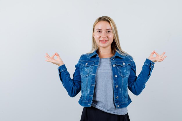 Jeune femme montrant un geste correct en t-shirt, veste en jean, jupe et semblant mignonne