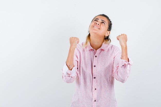 Jeune femme montrant le geste du gagnant en chemise rose et à la reconnaissance