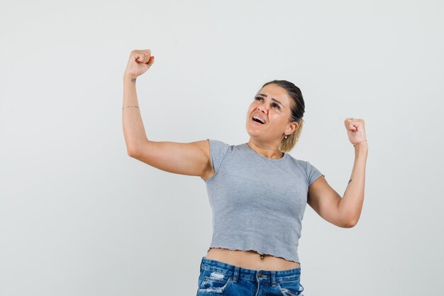 Jeune femme montrant le geste du gagnant en t-shirt, short et à la chance.