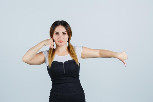 Jeune femme montrant le geste du téléphone et les pouces vers le bas