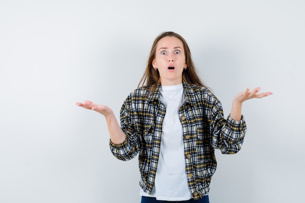 Jeune femme montrant un geste impuissant en t-shirt, veste et à la perplexité. vue de face.