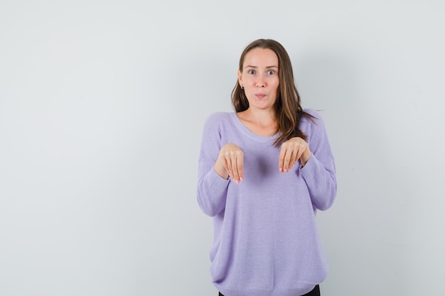 Jeune femme montrant le geste de lapin en chemisier lilas et à la mignon. vue de face. espace pour le texte