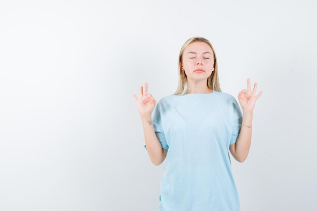 Jeune femme montrant un geste de méditation en t-shirt et semblant paisible