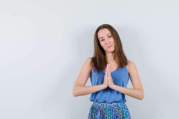 Jeune femme montrant le geste de namaste en maillot, jupe et à mignon