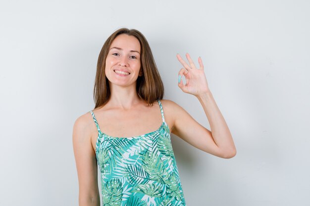 Jeune femme montrant un geste ok et l'air joyeux. vue de face.