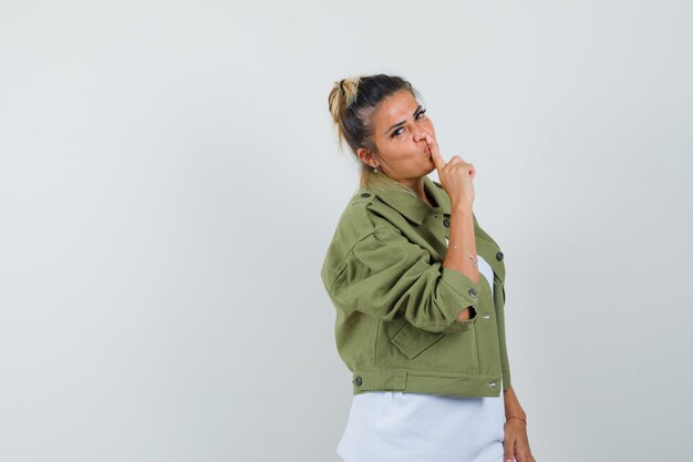 Photo gratuite jeune femme montrant le geste de silence en veste t-shirt et à l'élégante