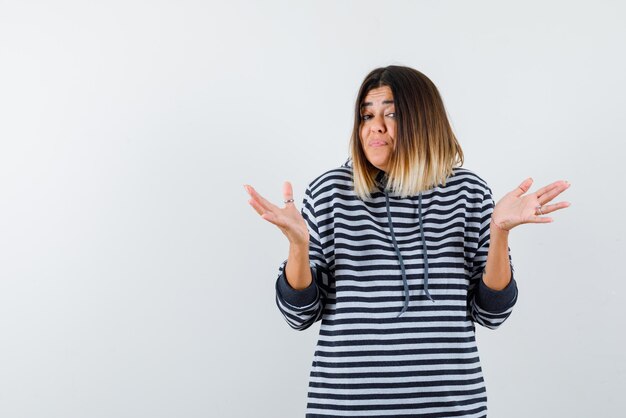 Jeune femme montrant je ne sais pas geste de la main sur fond blanc