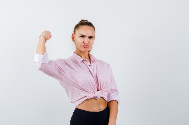 Jeune femme montrant les muscles du bras en chemise décontractée, pantalon et à la confiance