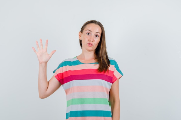 Jeune femme montrant la paume en t-shirt et à l'espoir, vue de face.