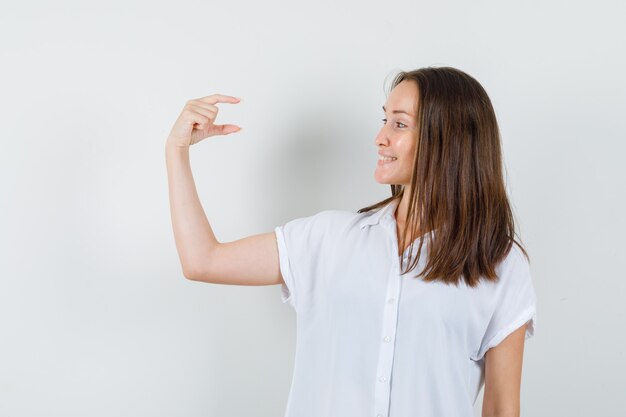 Jeune femme montrant une petite taille en chemisier blanc et à la satisfaction