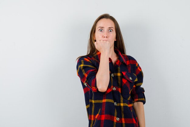 Jeune femme montrant le poing fermé en chemise décontractée et à la vue de face, puissante.