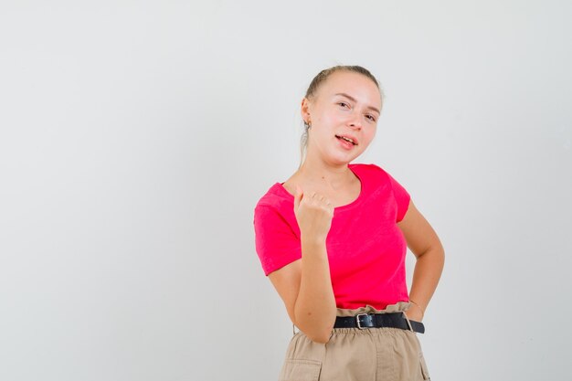 Jeune femme montrant le poing fermé en t-shirt et pantalon et à la chance