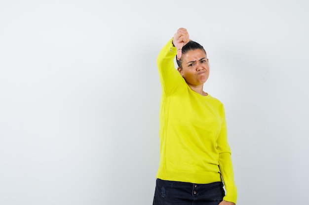 Jeune femme montrant le pouce vers le bas en pull, jupe en jean et à la nostalgie