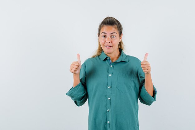 Jeune femme montrant le pouce vers le haut en chemise bleue et à la joie