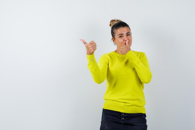 Jeune femme montrant le pouce vers le haut dans un pull, une jupe en jean et l'air confiant