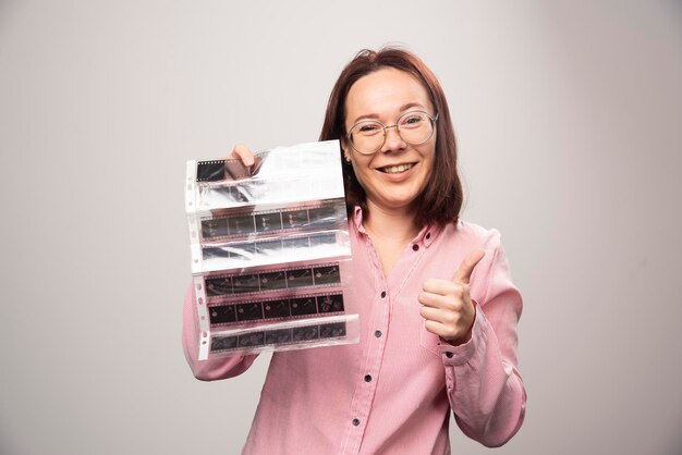 Jeune femme montrant un pouce vers le haut et tenant une bande photo sur un fond blanc. photo de haute qualité